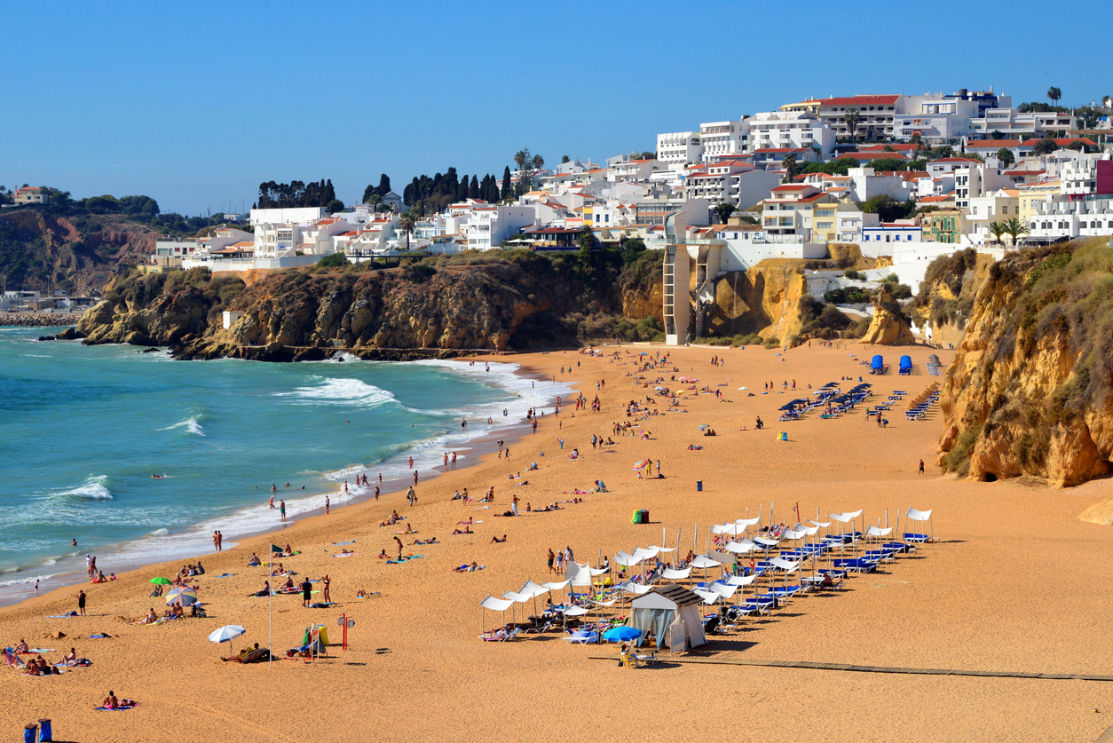 Albufeira, Algarve, Portugal: the town develops above the ocean-front cliffs by the beaches known as  Praia dos Pescadores and Praia do Peneco - many people on the beaches, none a central subject of the image